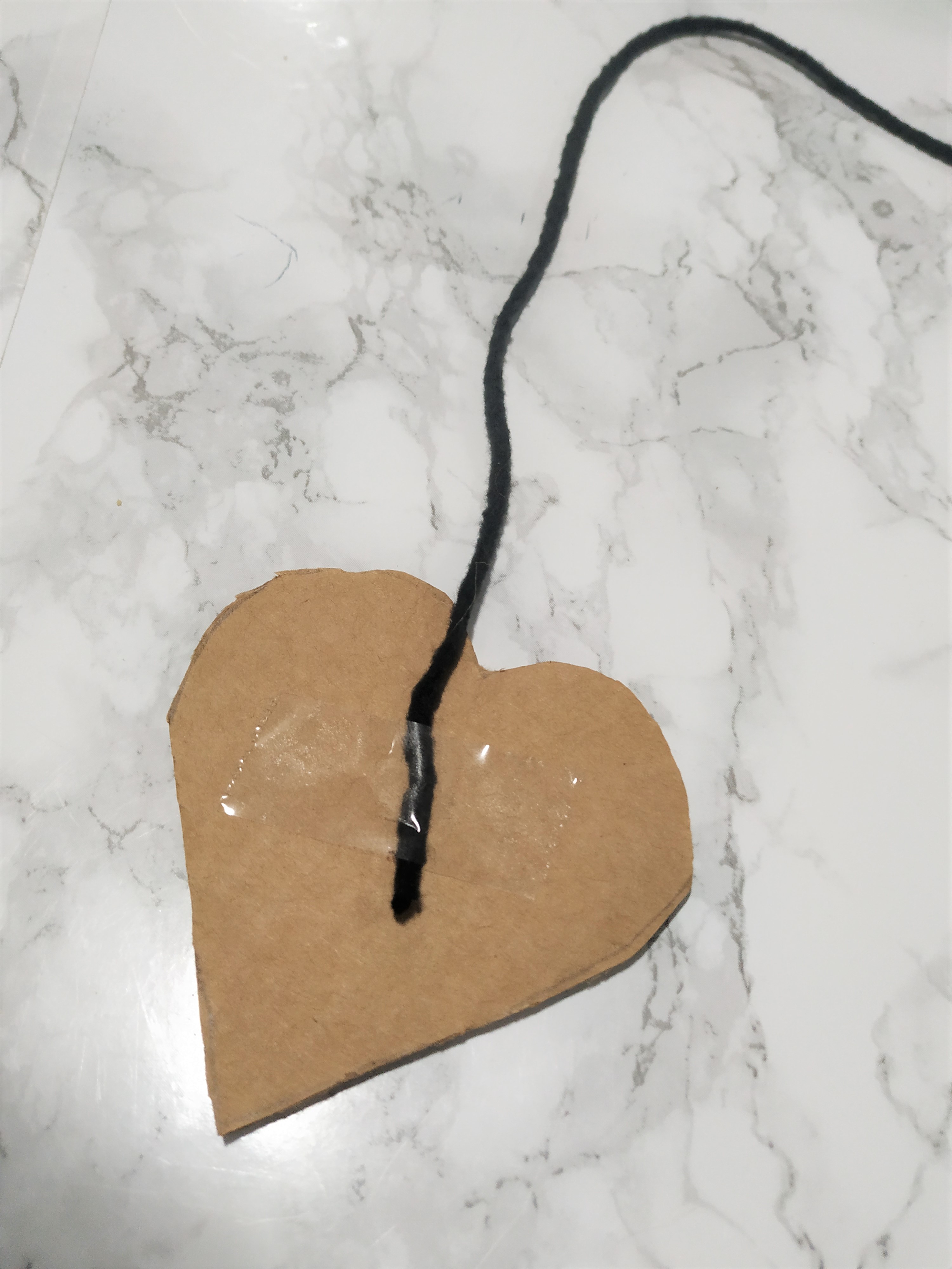 Taping a piece yarn onto a cardboard heart.
