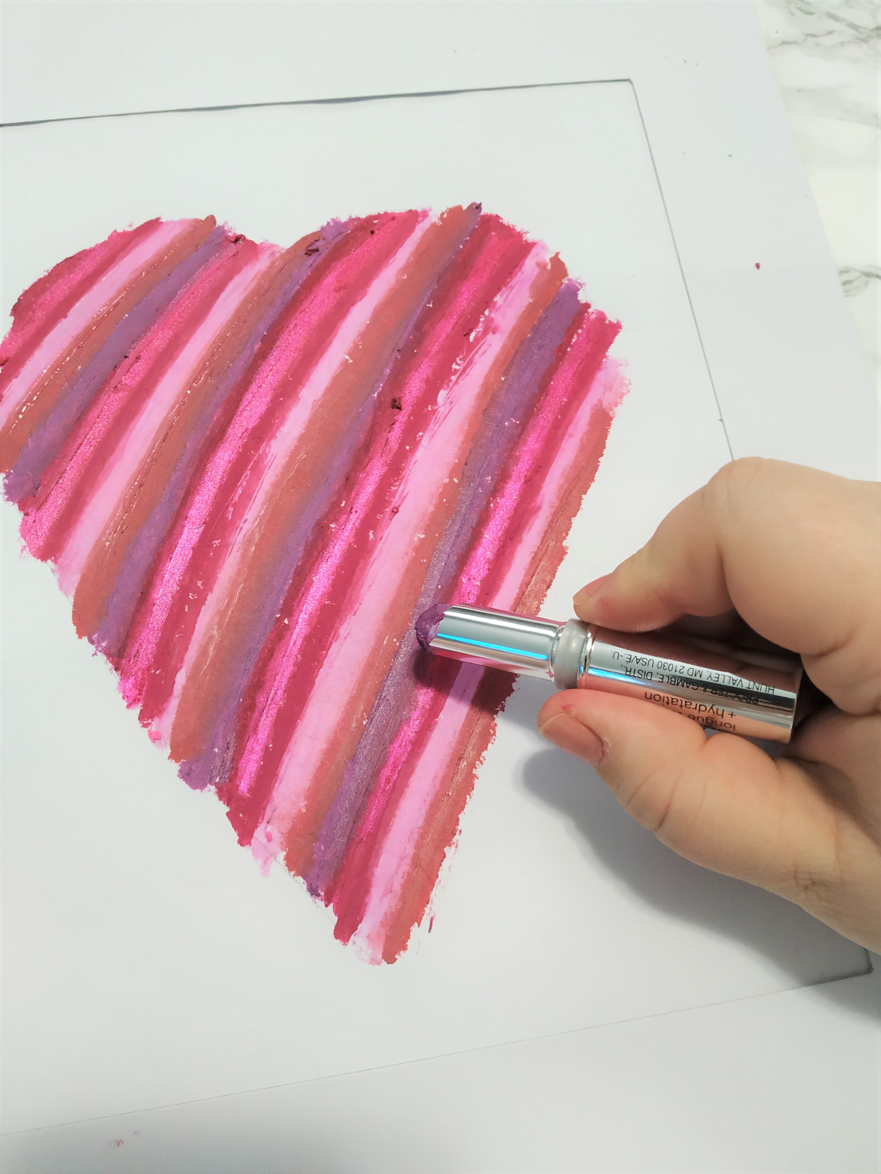 Hand holding a lipstick ready to make lines on a heart.