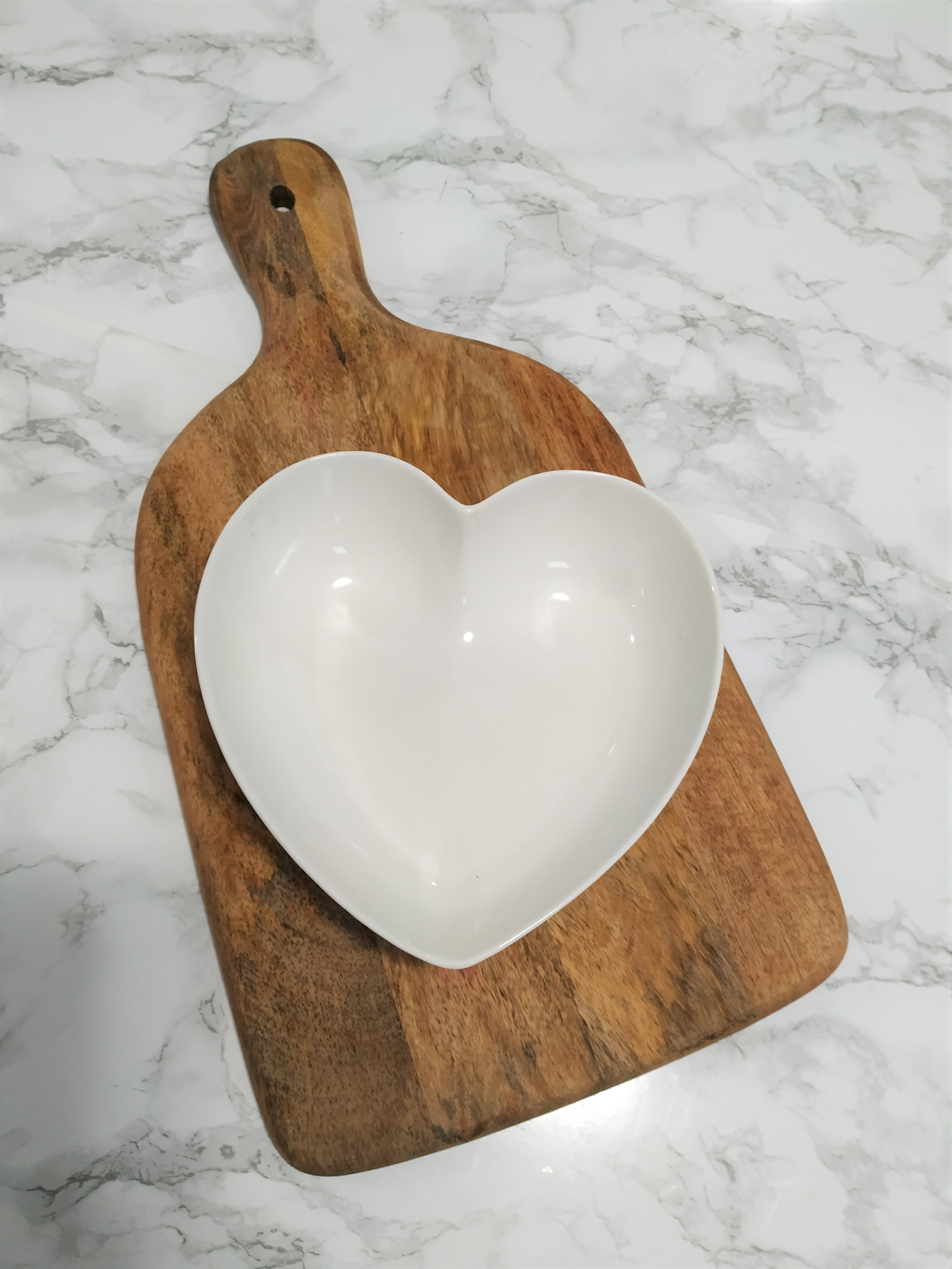 A heart bowl placed on top of a charcuterie board.