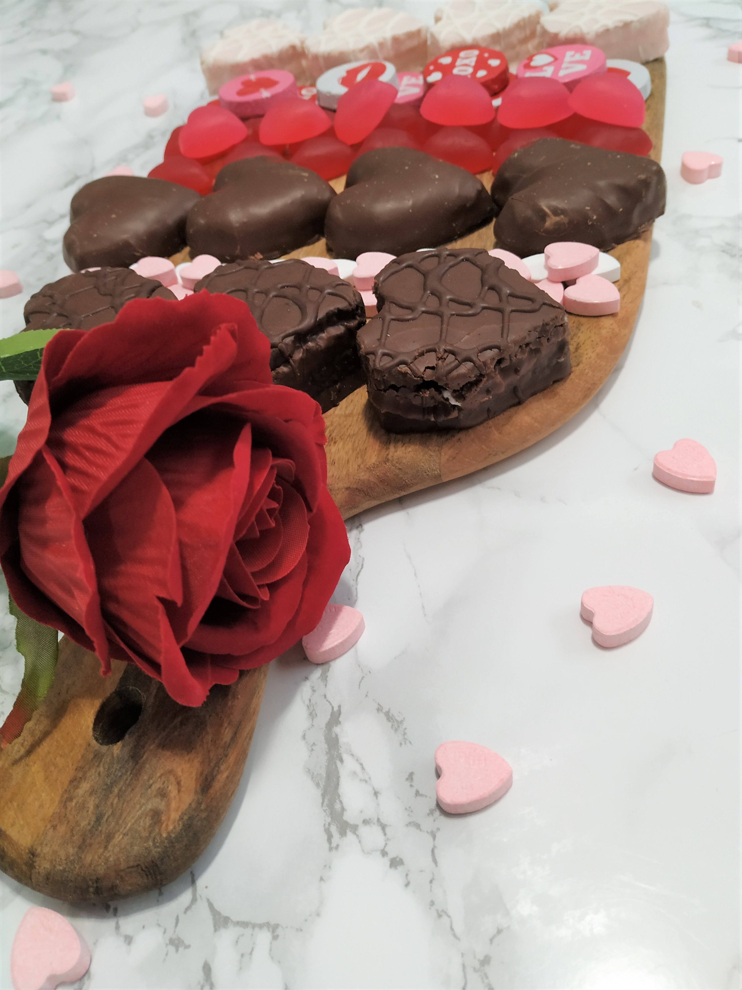 Angled view of a candy charcuterie board decorated with a red rose.