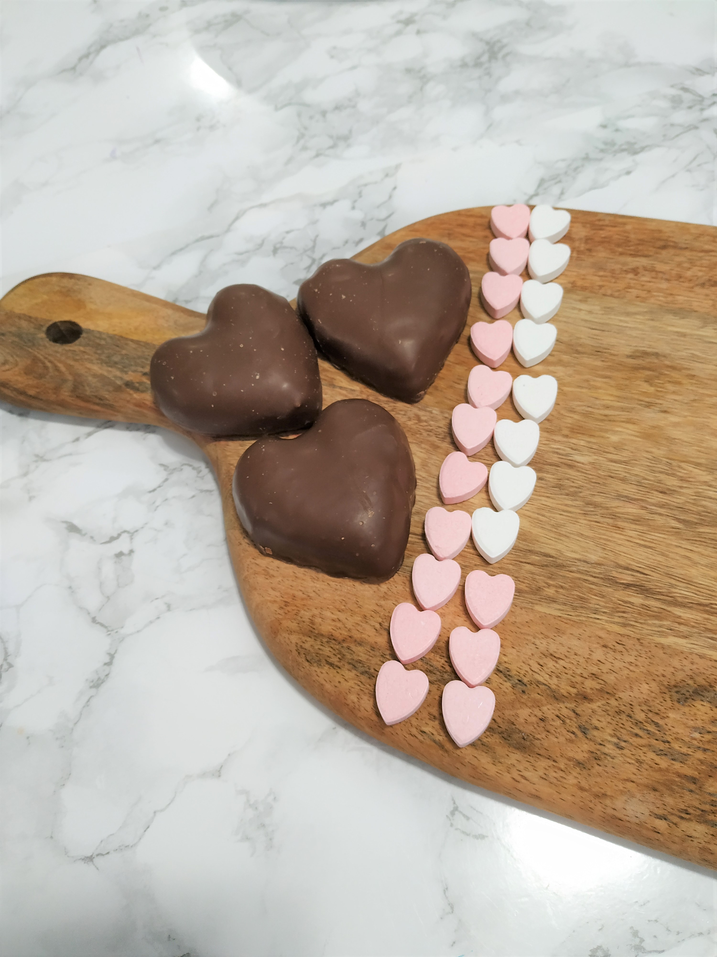 Putting pink and white hearts on the candy charcuterie board.