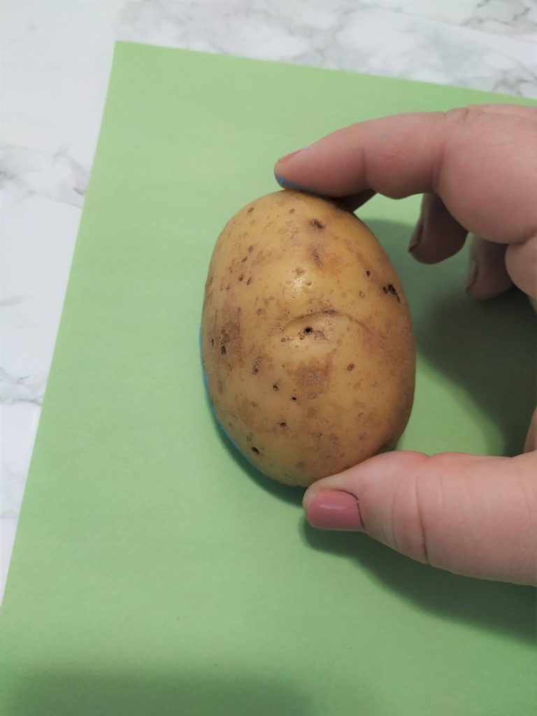 Pressing down the potato onto a piece of paper.