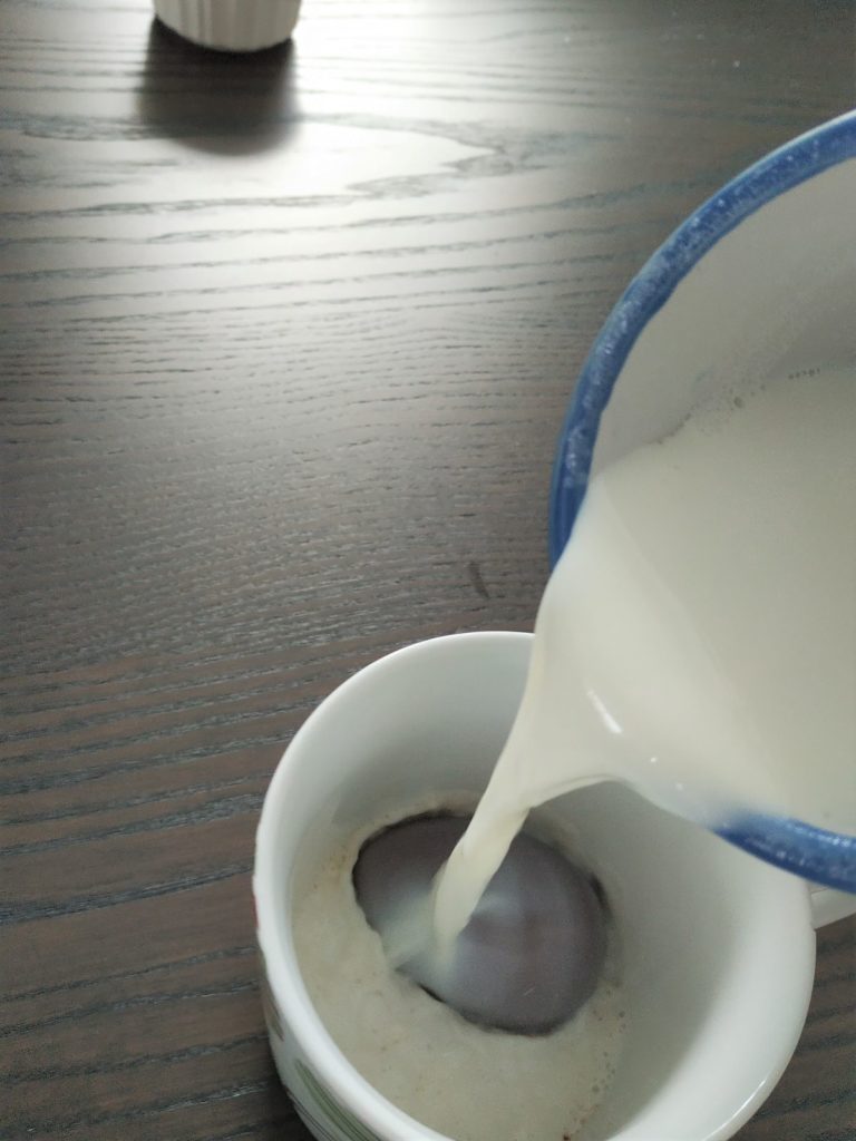 Pouring hot milk over the hot chocolate bomb.