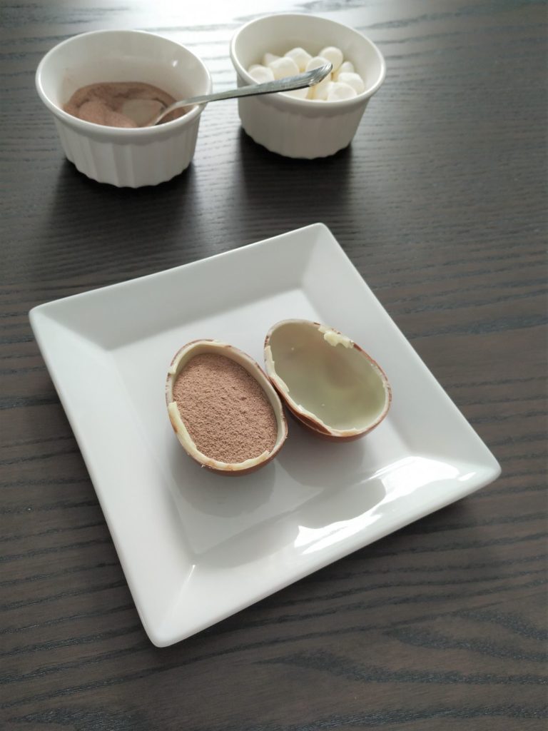 Filling a kinder egg shell with powdered hot chocolate.