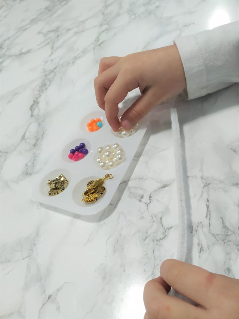 Picking up a bead from a tray.