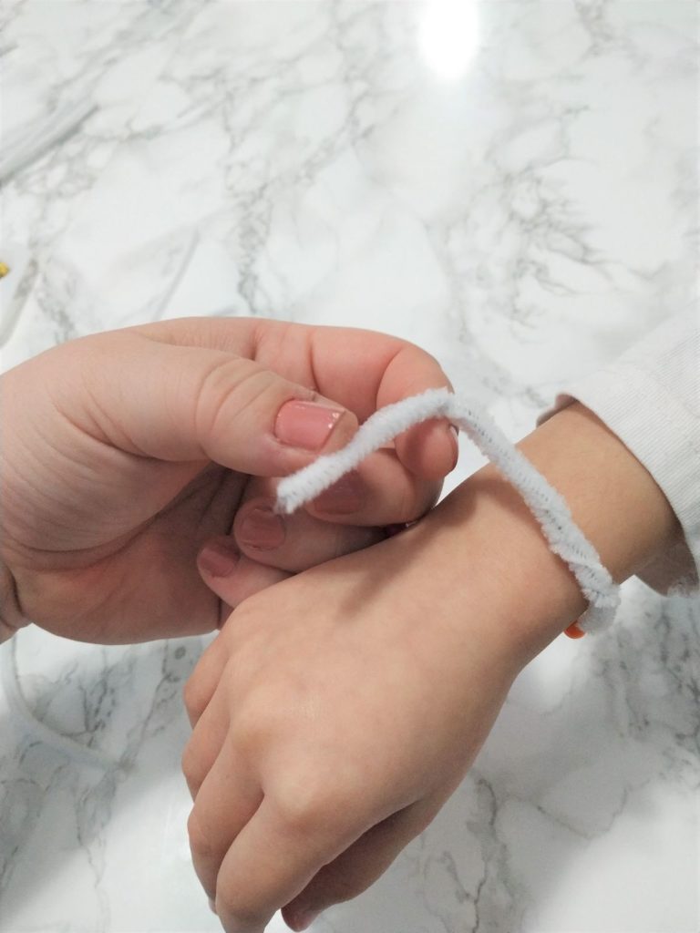 Twisting the ends of the pipe cleaner to form a bracelet.