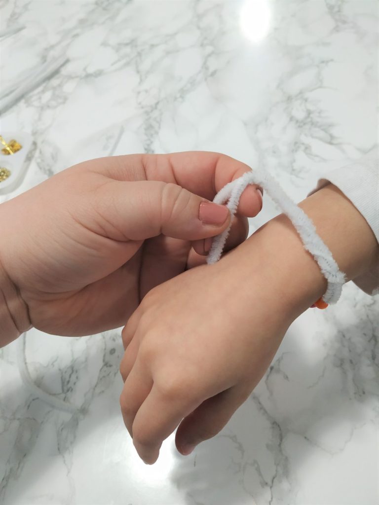 Twisting the ends of the pipe cleaner to form a bracelet.