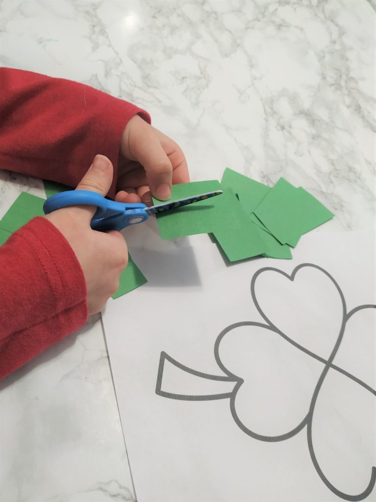 Cutting green paper into small shapes.