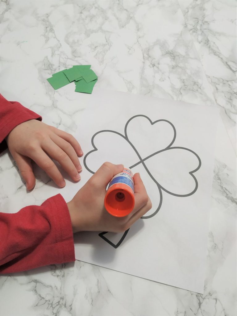 Adding glue to the shamrock coloring page.