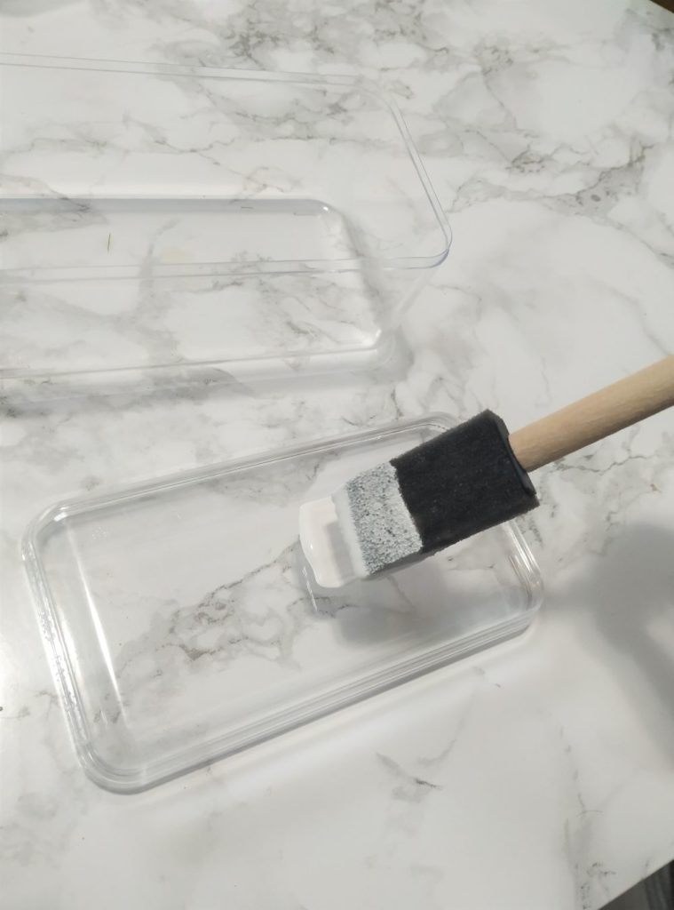 Painting the plastic lid with white paint.