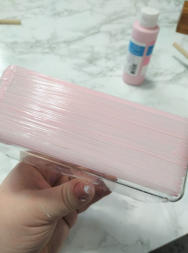 Painting the bottom of the plastic box pink.