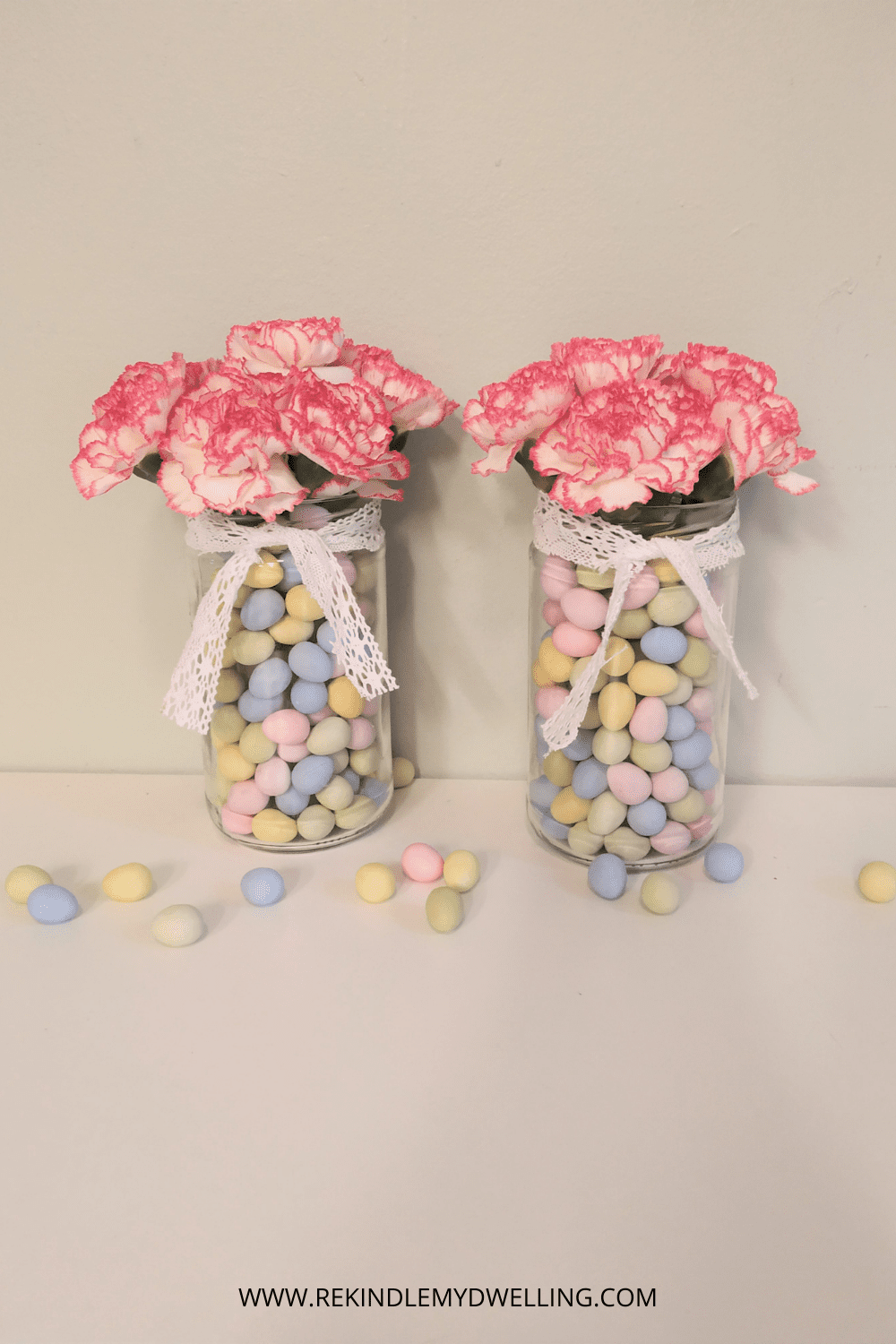 Easter candy jars with flowers, ribbon and candy eggs scattered around.