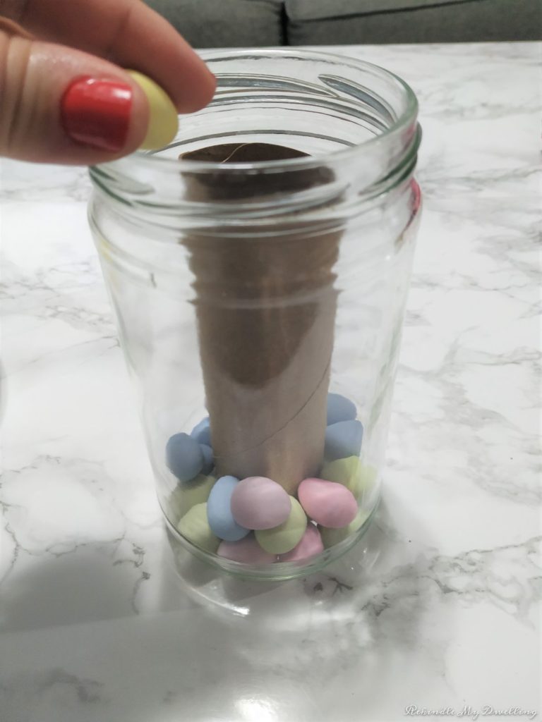 Mason jar getting filled with candy eggs.