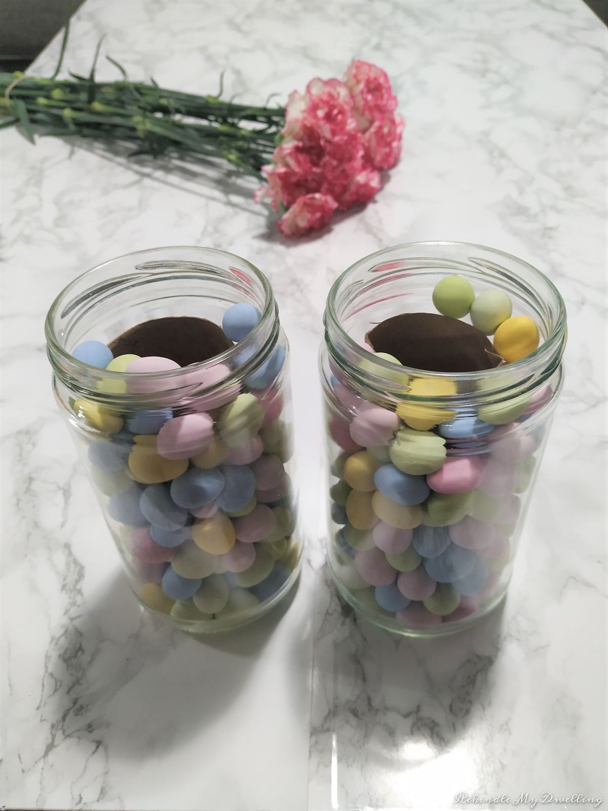 Mason jars filled with Easter candy placed next to fresh flowers.