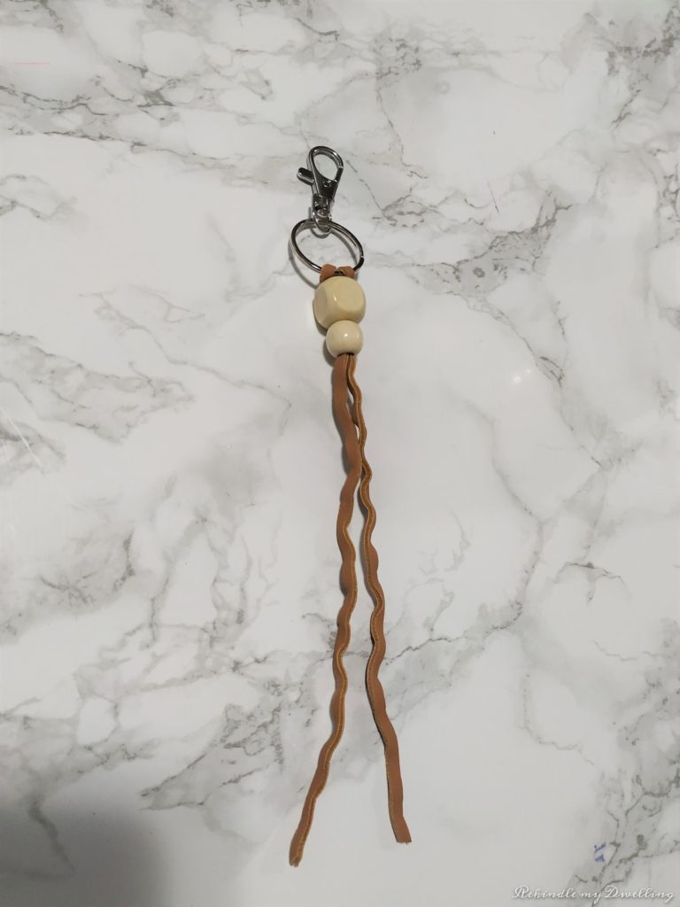 Adding wood beads onto a leather string.