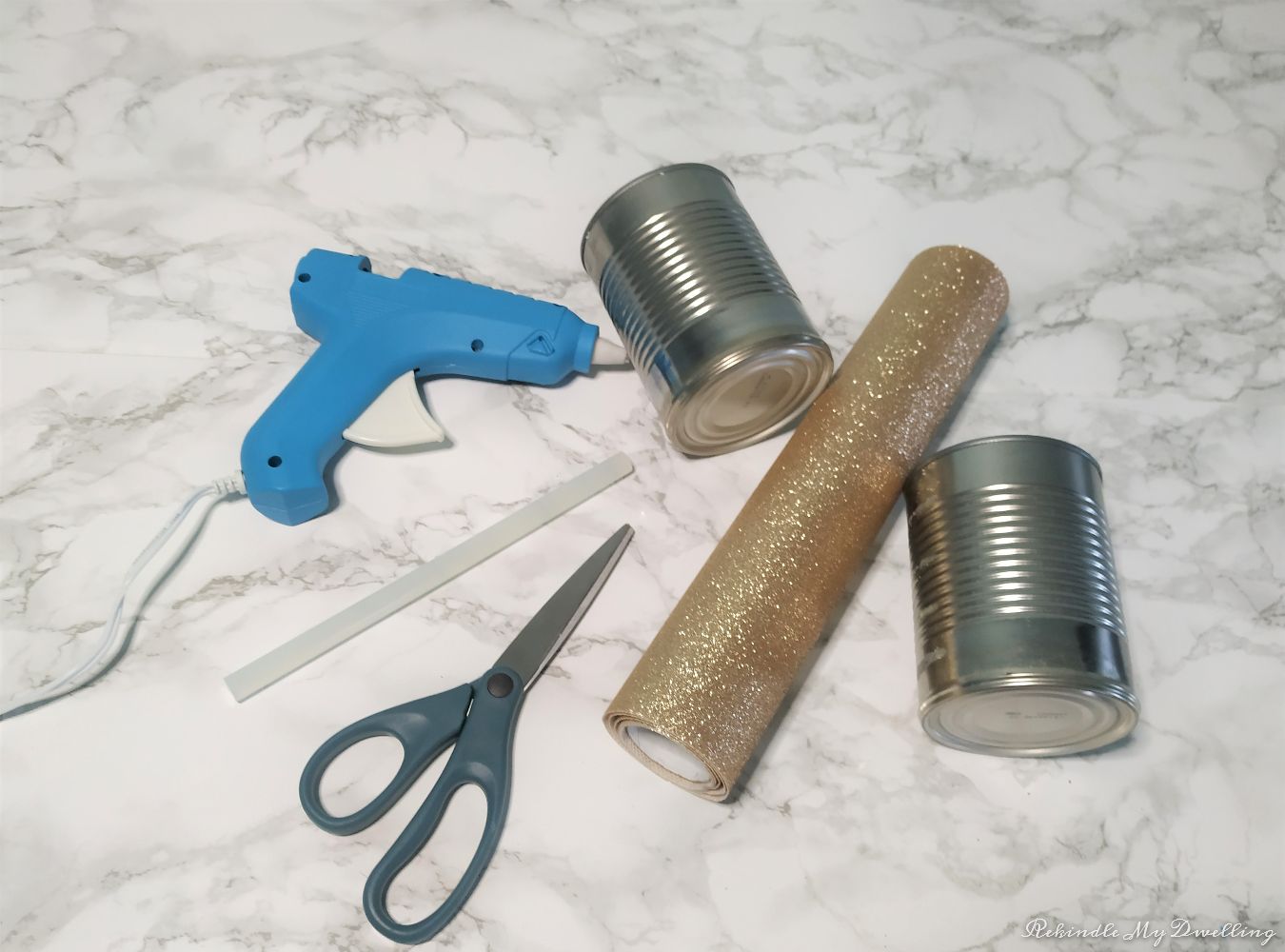 Materials needed for make up organizers including tin cans, fabric, scissors and hot glue.