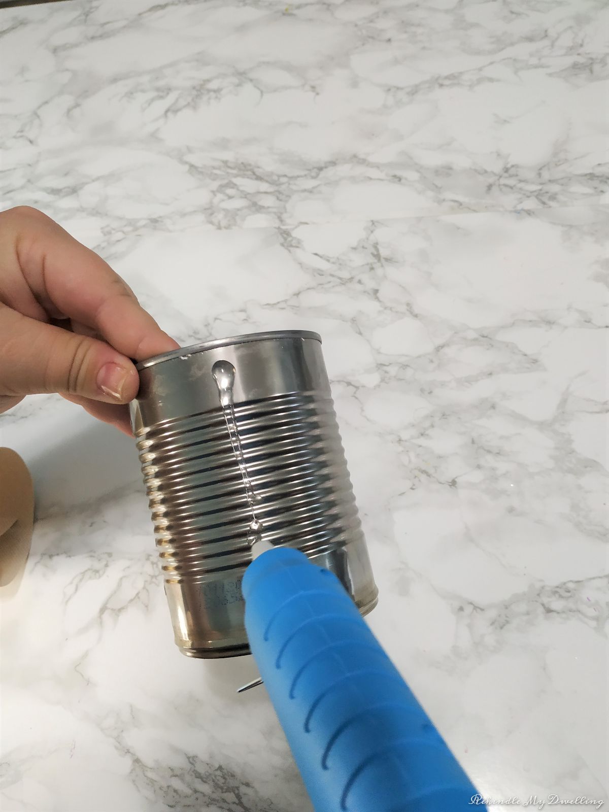Adding hot glue on a tin can.