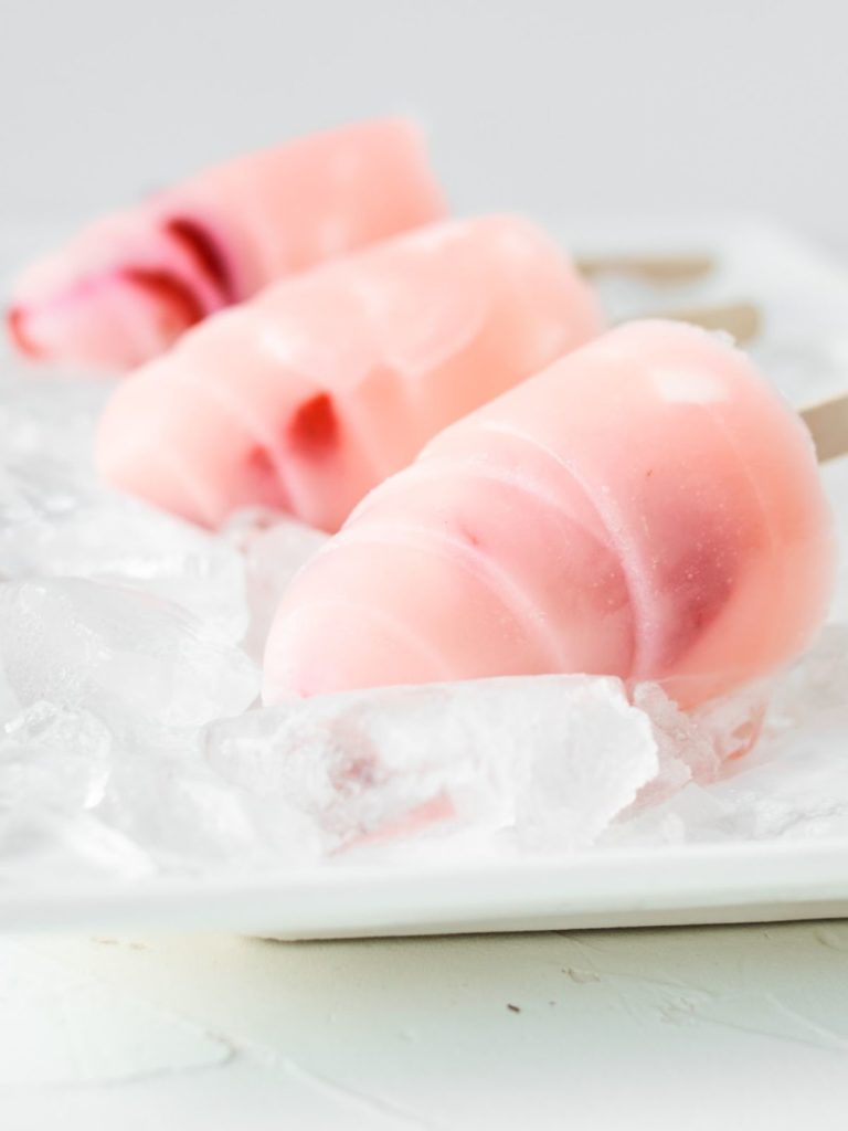 Strawberry popsicles on ice.