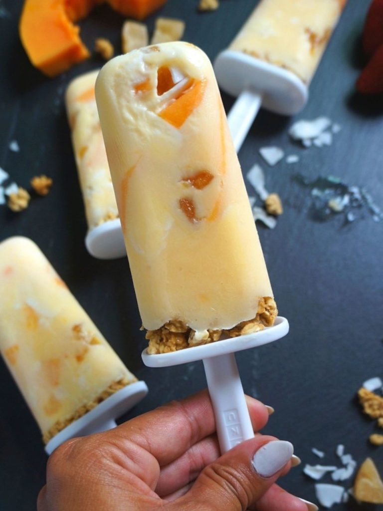 Summer popsicle recipes holding a mango popsicle