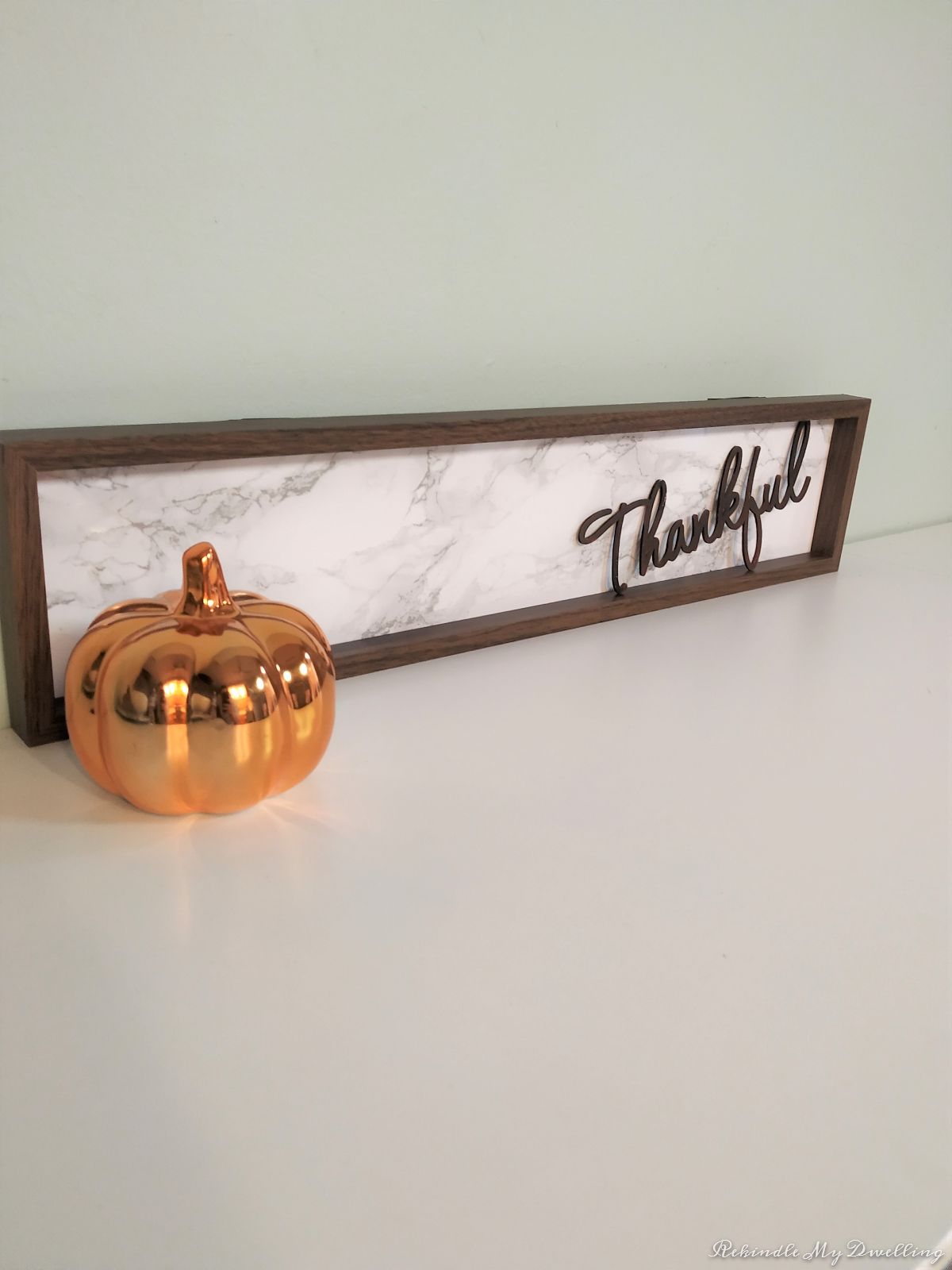 DIY thankful wood sign displayed next to a pumpkin.