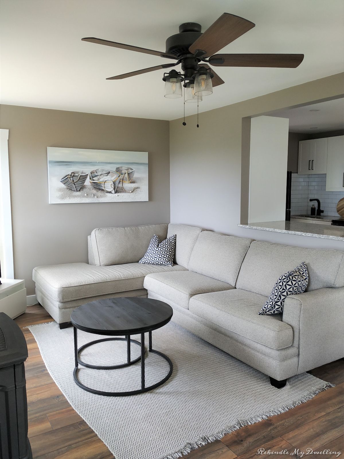 Cottage makeover showing finished living room with couch, painting and ceiling fan. 