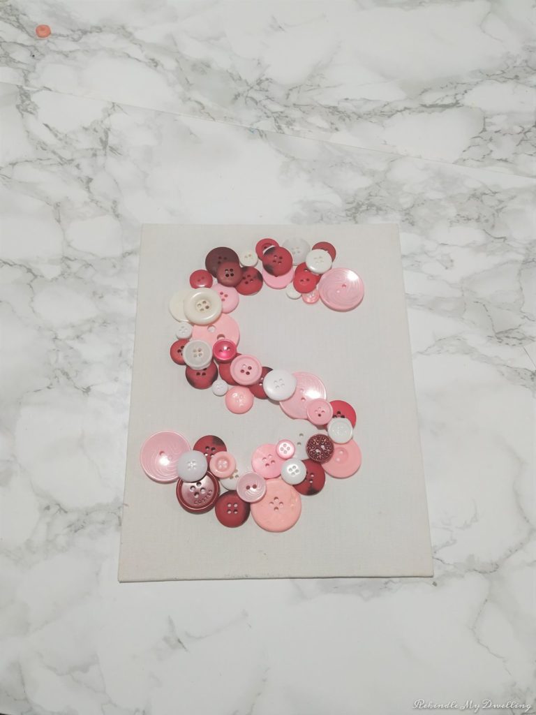 Pink button monogram letter on canvas.