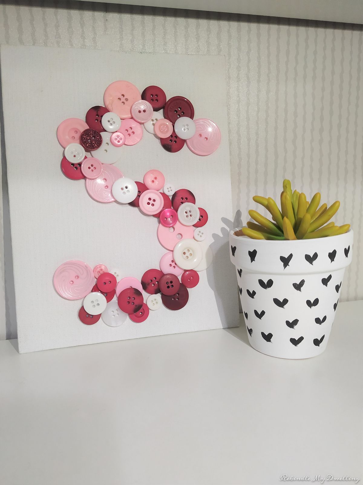 Pink button monogram letter on canvas.