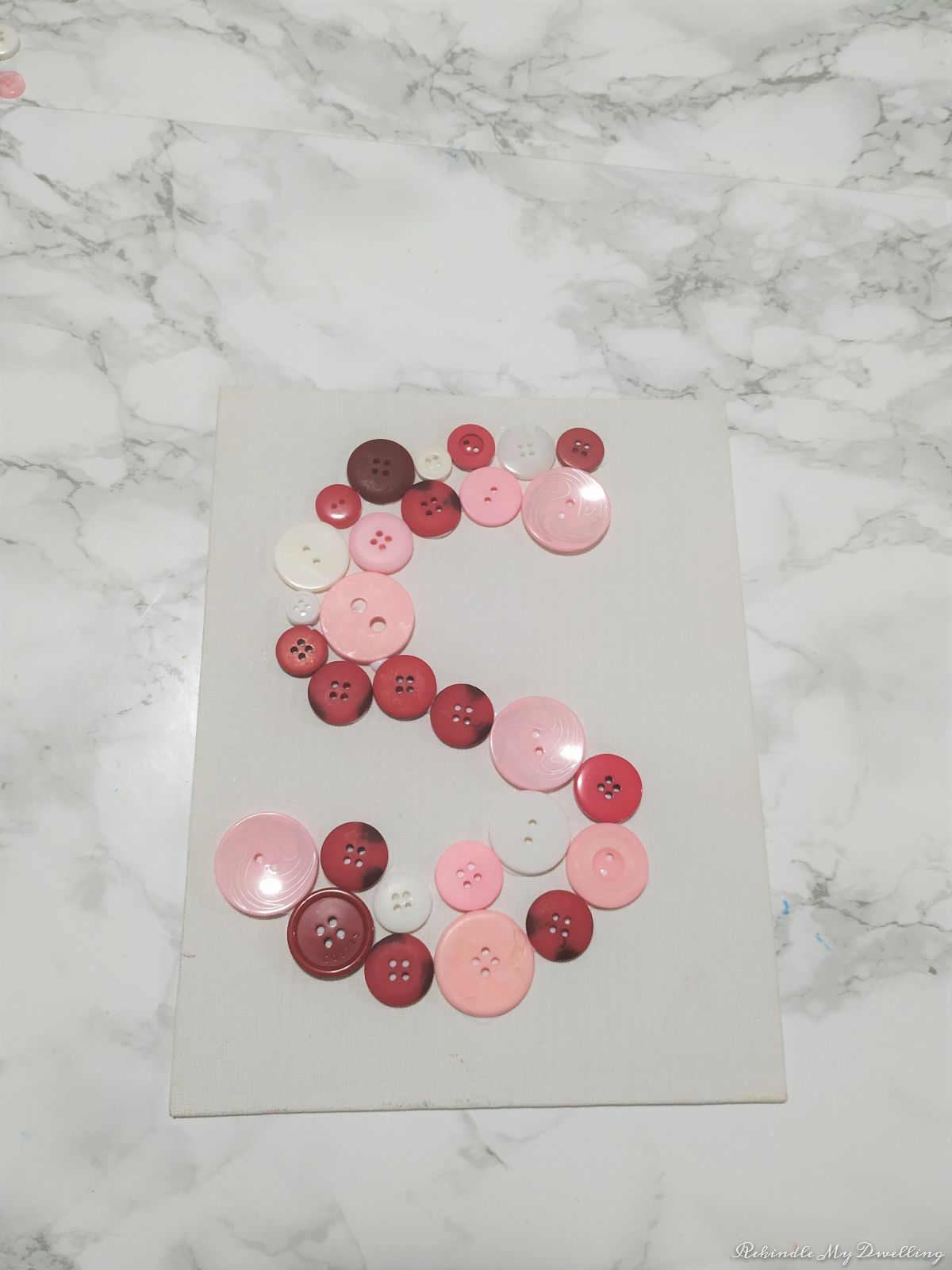 Adding more buttons around the Pink button monogram letter.