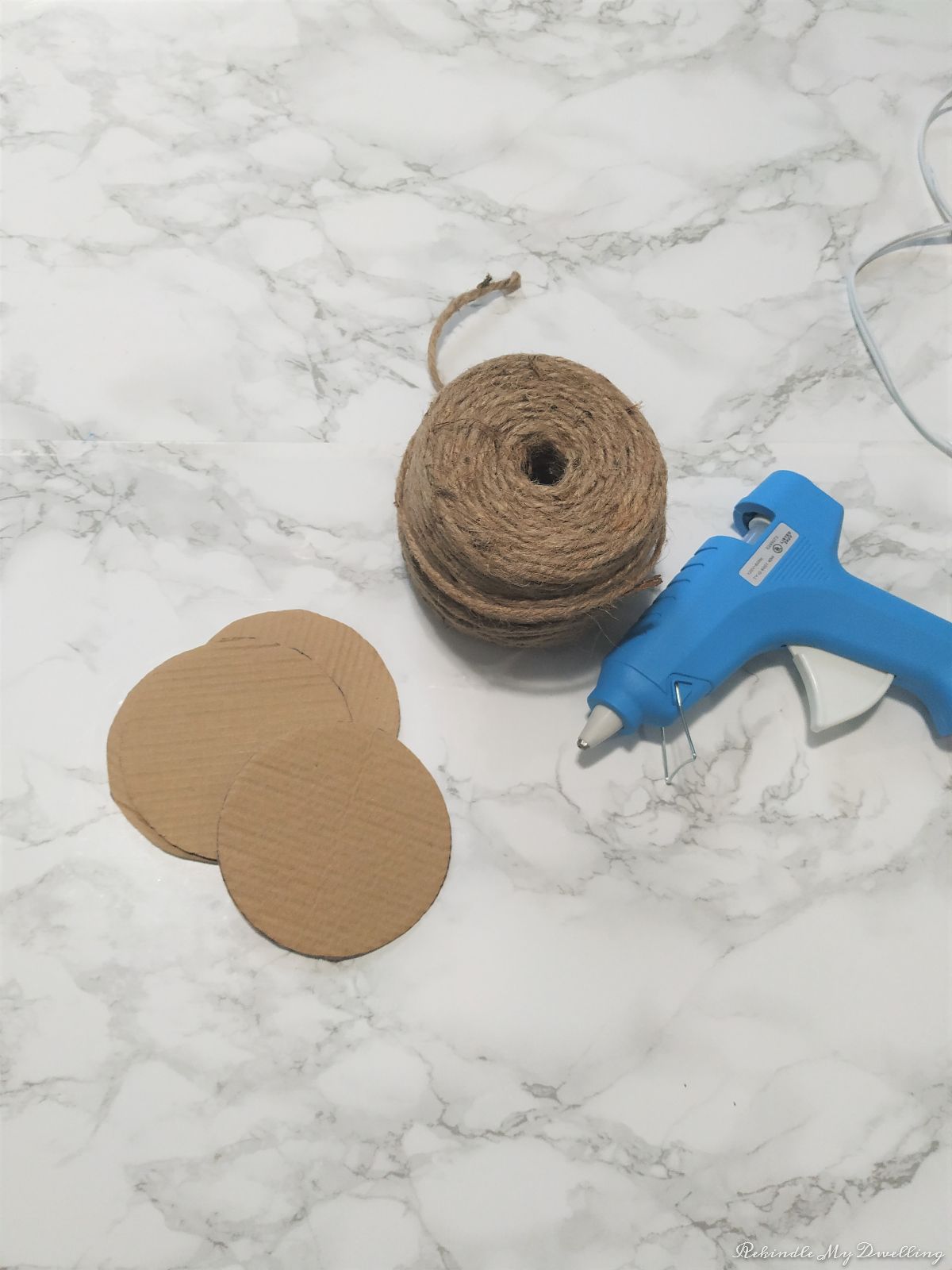 Materials needed to make DIY rope coasters, including cardboard cut outs, rope and a glue gun.