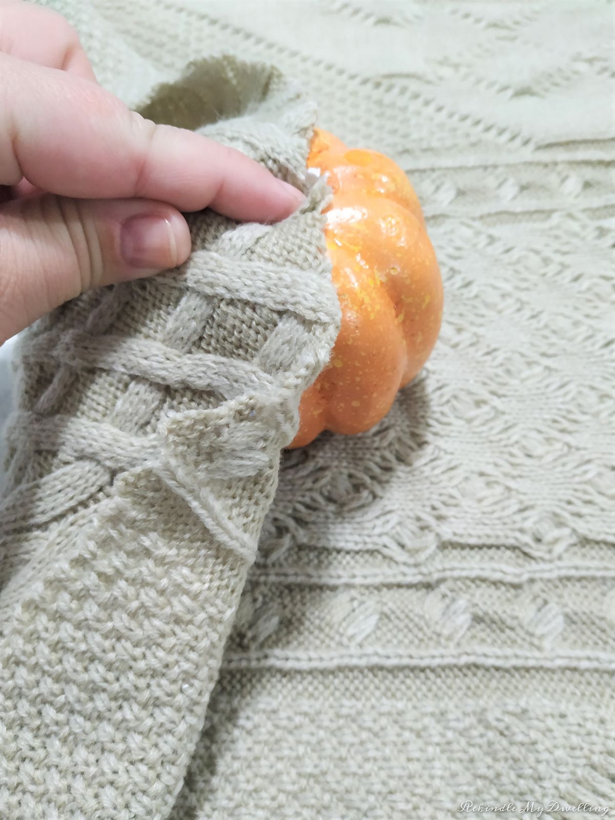 Pushing the sweater into the top of the foam pumpkin.
