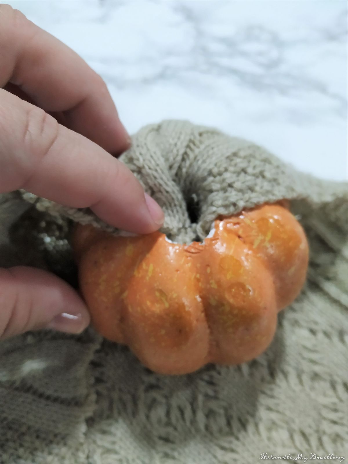 Pushing the sweater into the top of the foam pumpkin.