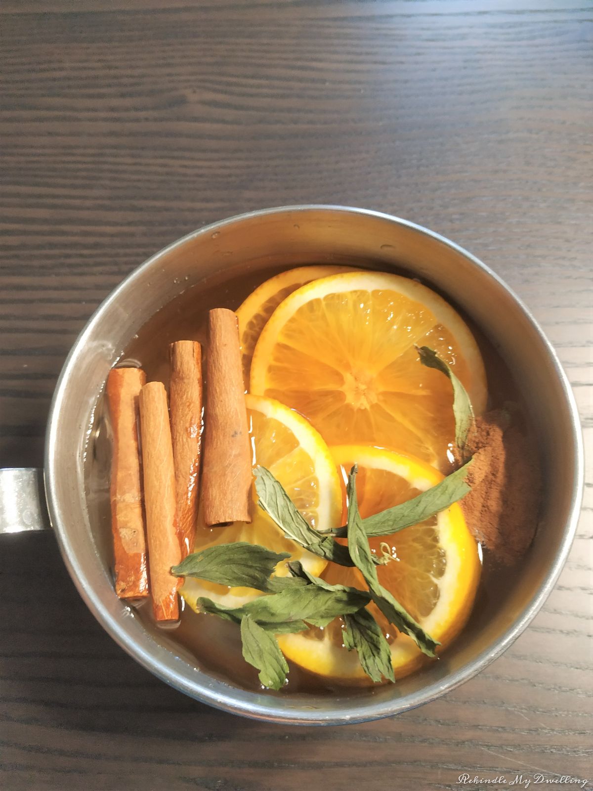 Pot filled with orange slices, cinnamon, mint and vanilla.