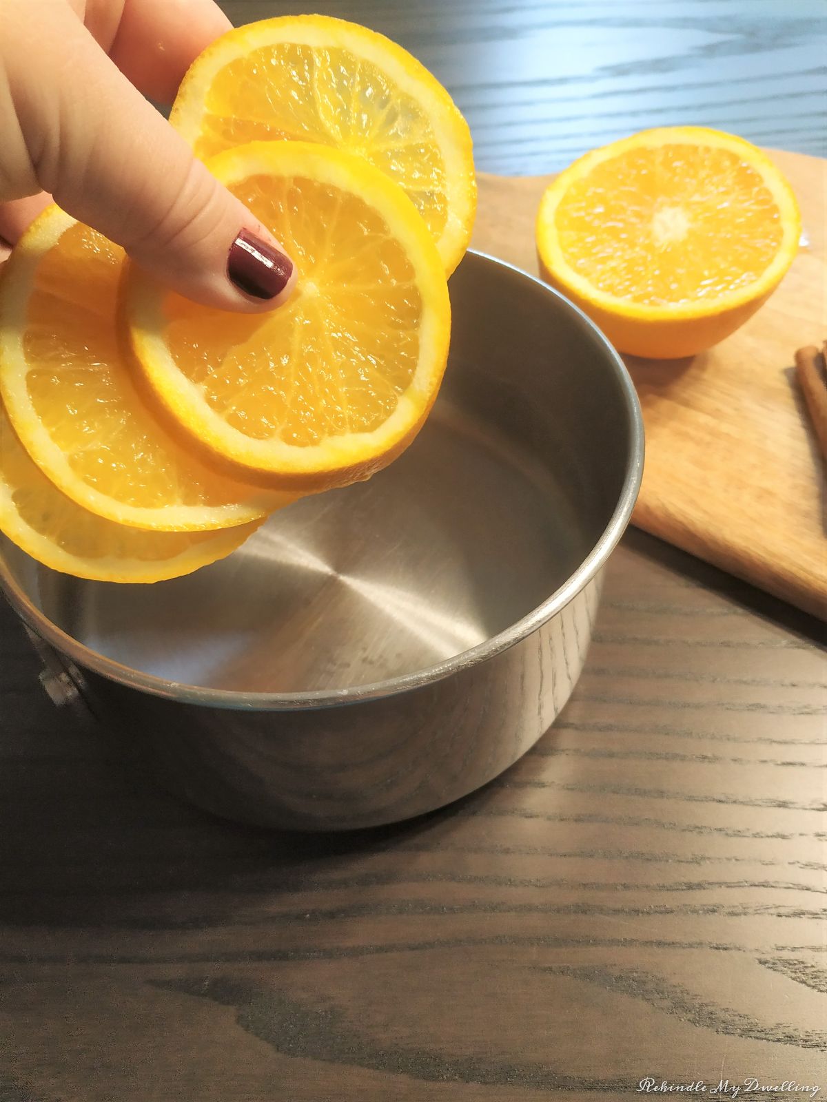 Adding orange slices into the pot of water.