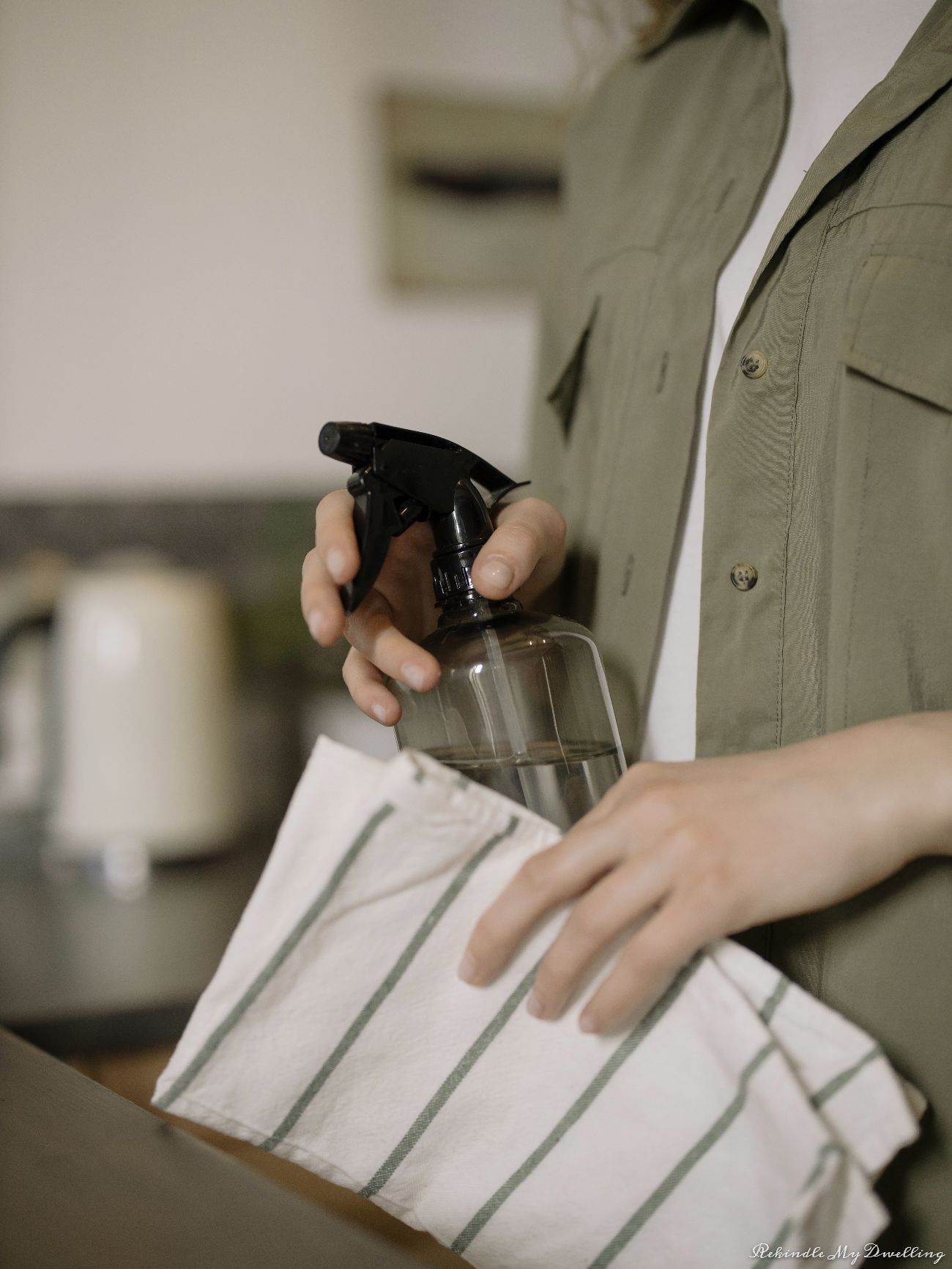 Holding a dish towel and spray bottle.