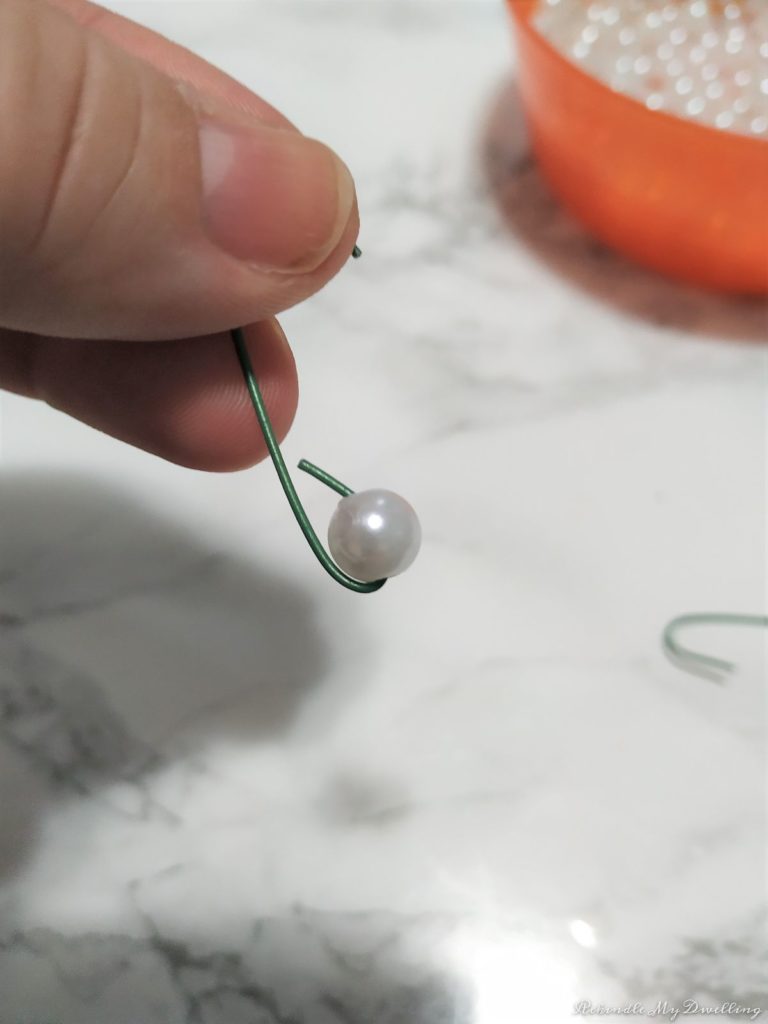 Adding a pearl onto an ornament hook.