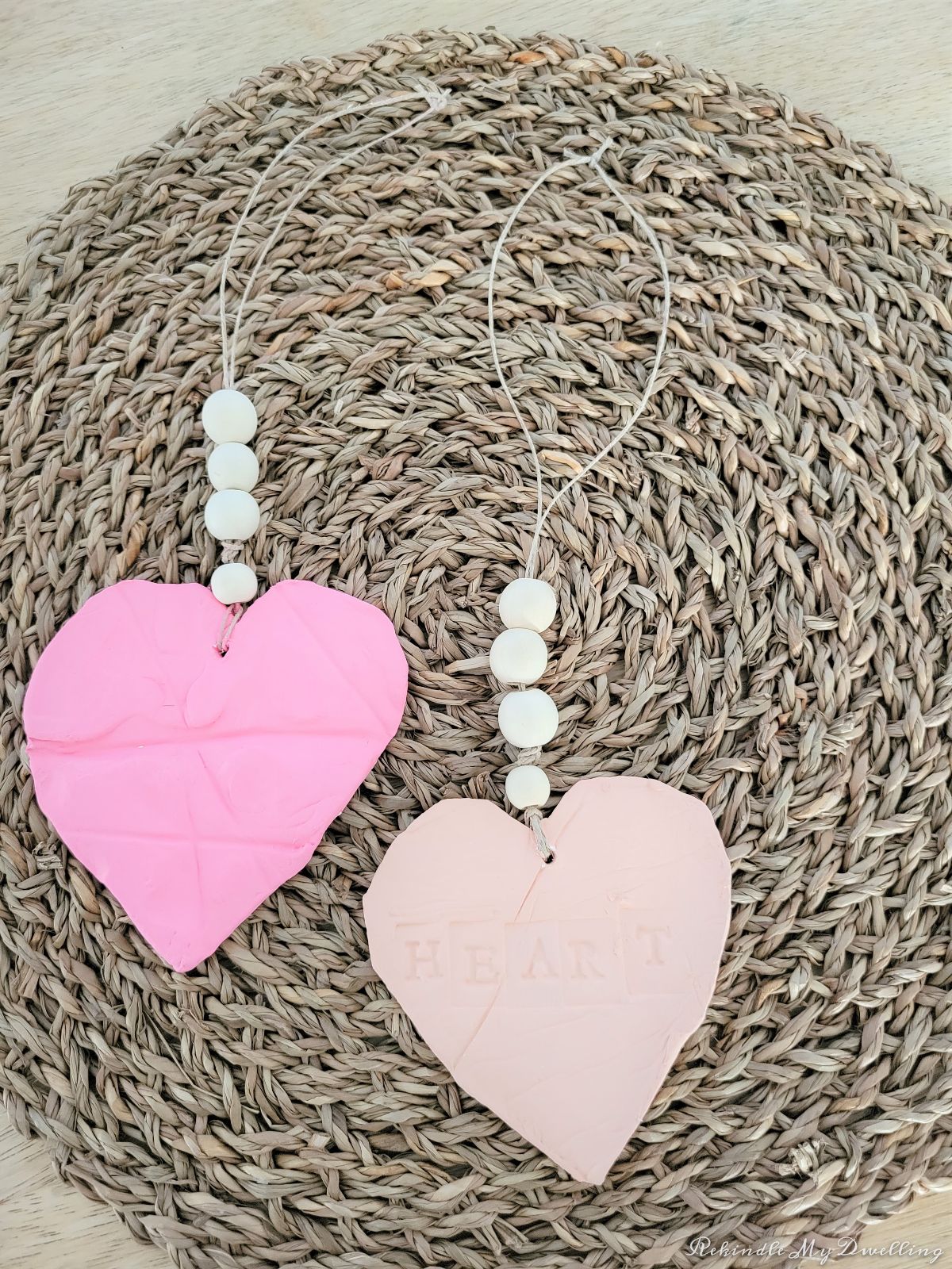 Heart ornaments with wood beads laying on a place mat.