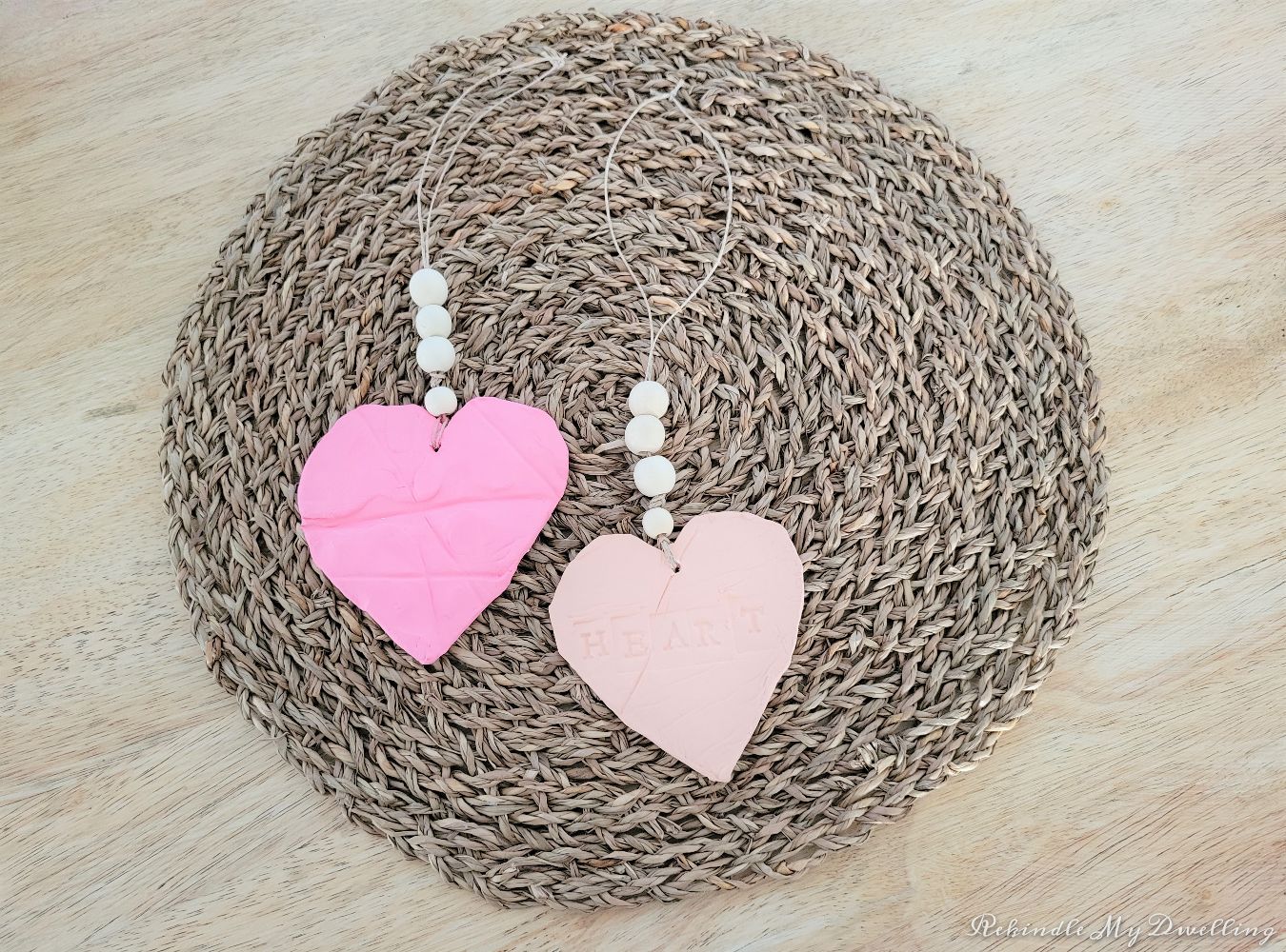 Heart ornaments with wood beads laying on a place mat.