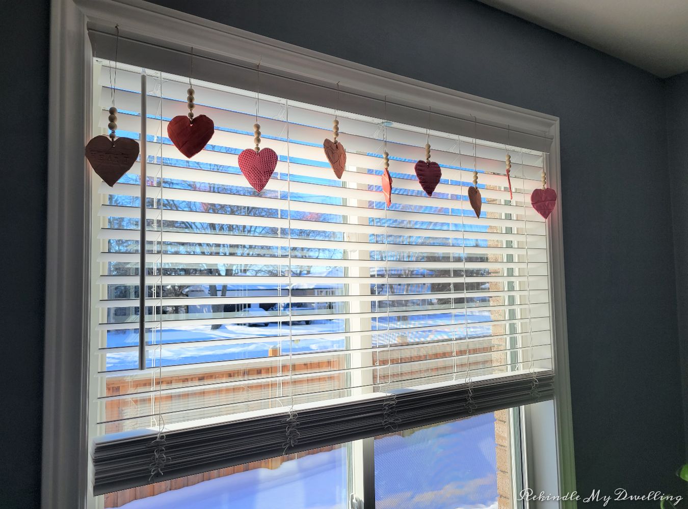 Heart ornaments with wood beads hung from a window.