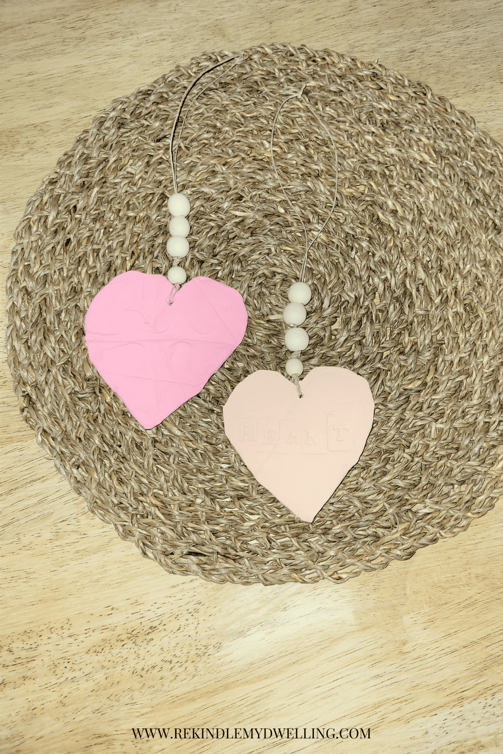 Heart ornaments with wood beads laying on a place mat.