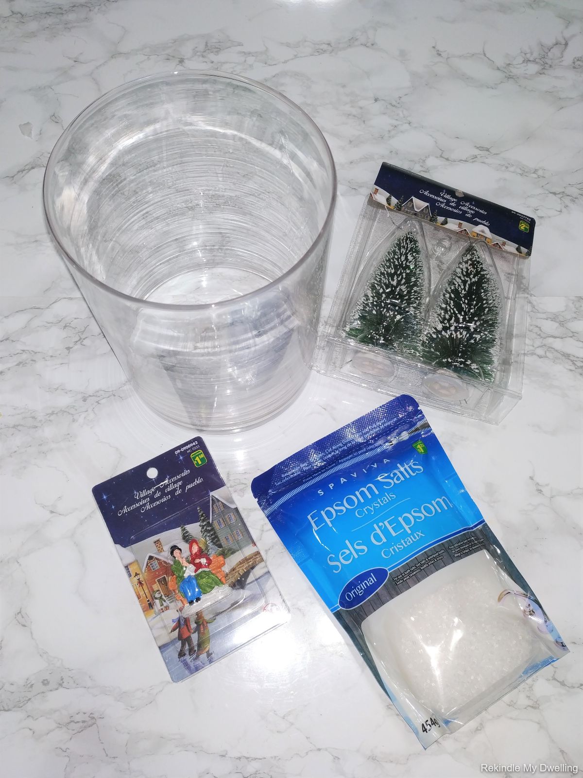 Materials needed to make a dollar store decorative Christmas jar including a glass jar, epsom salts and decorative figurines.