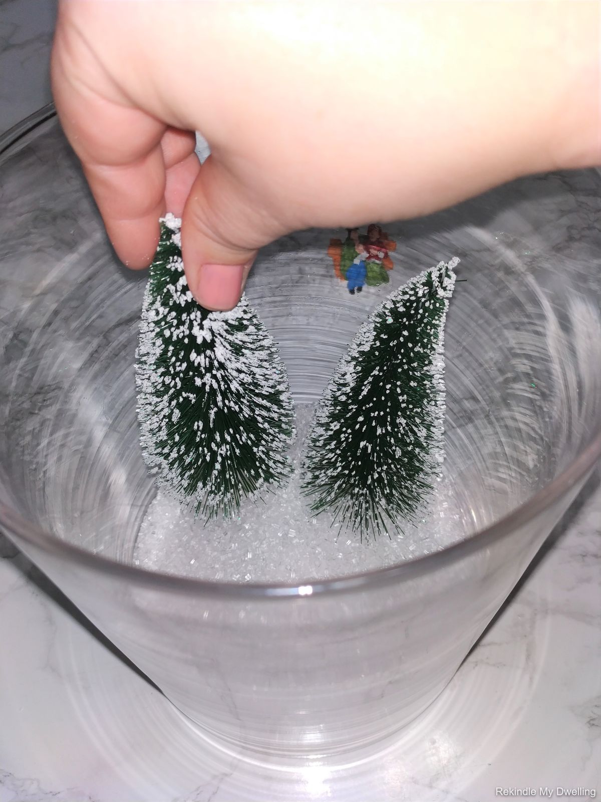 Placing bottle brush trees into the glass jar.