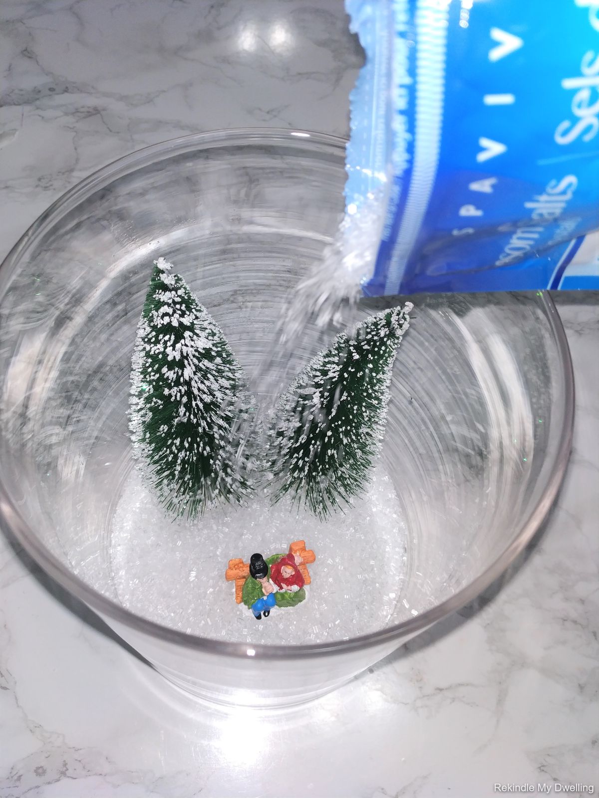 Pouring Epsom salts into the dollar store decorative Christmas jar.