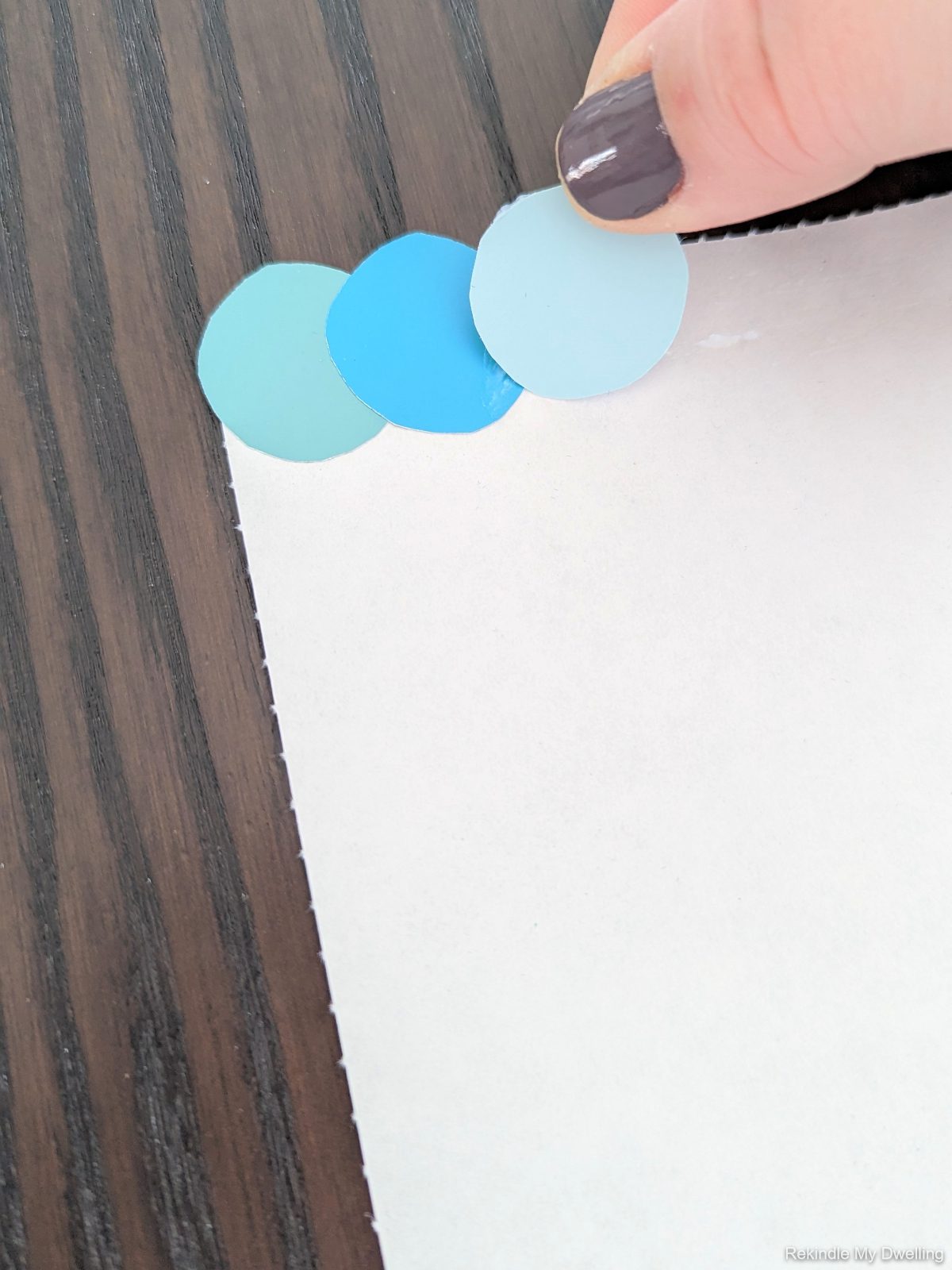 Gluing round paint chips onto a paper.