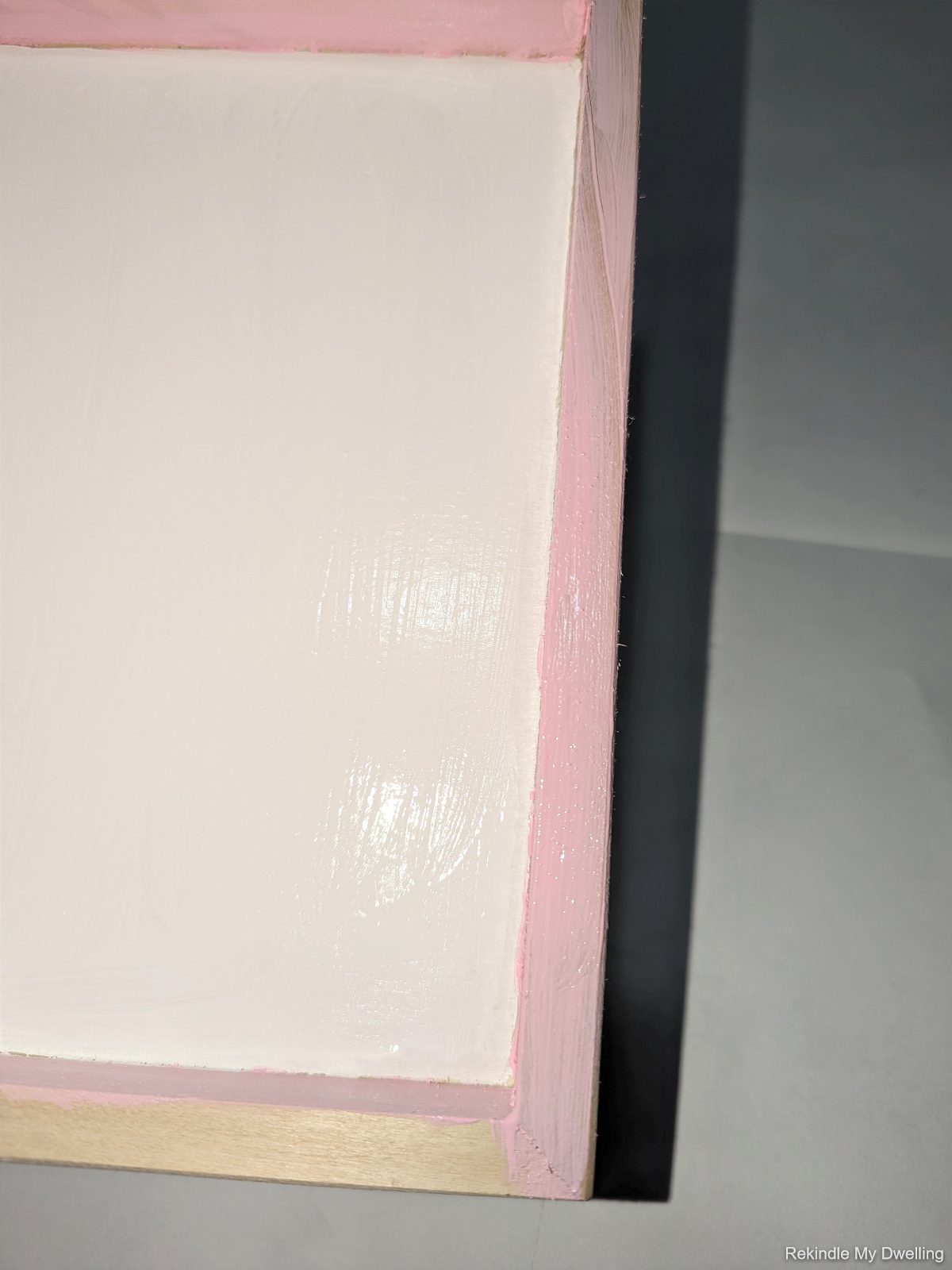 Painting the outside of the wood canvas pink.