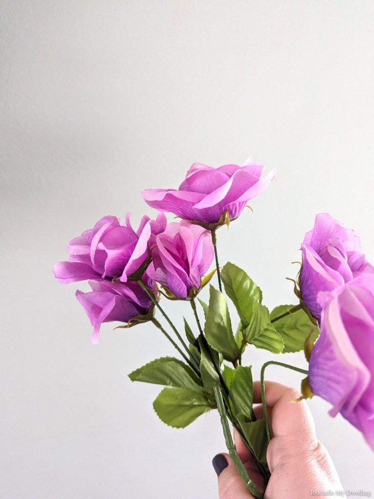 Hand holding faux purple flowers.