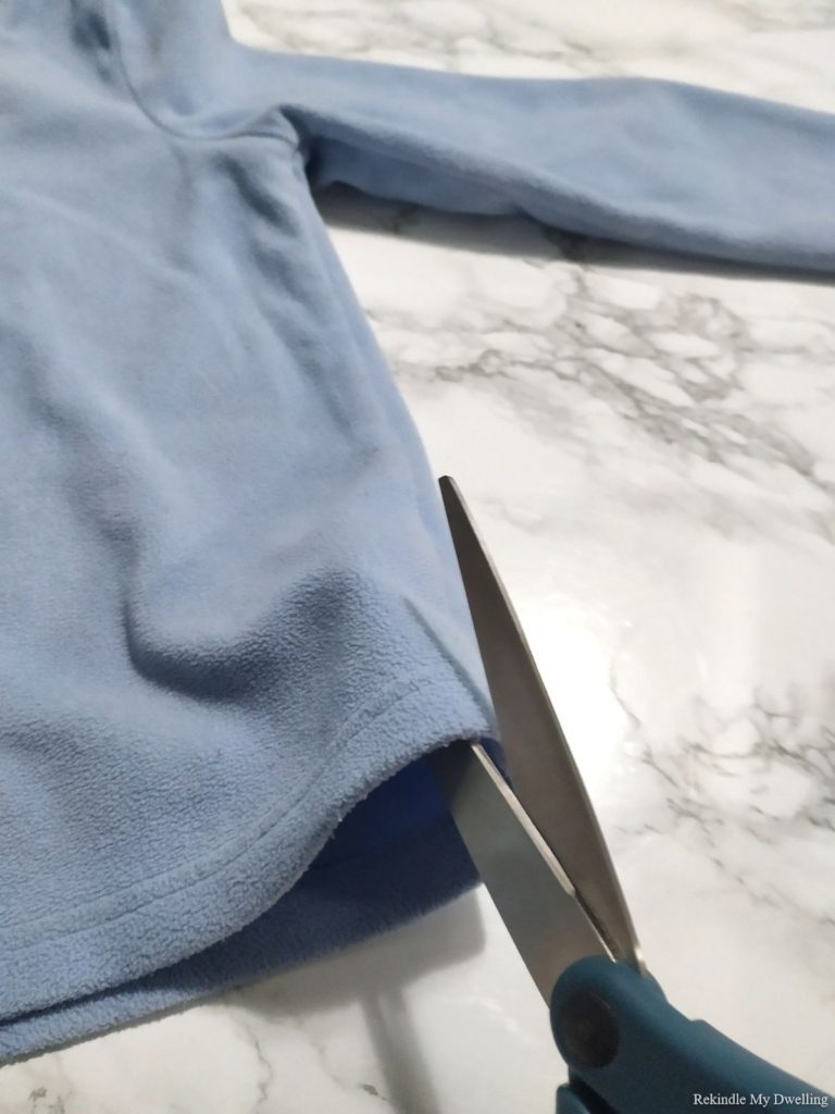 Cutting a blue sweater.