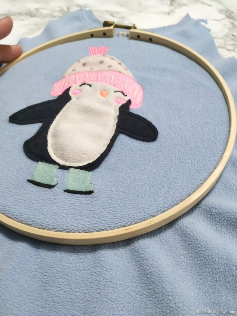 Placing an embroidery hoop over a penguin picture.